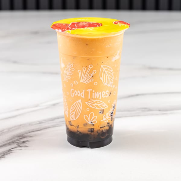 A Vietnamese iced coffee with boba in a clear cup with a yellow lid, on a marble surface.